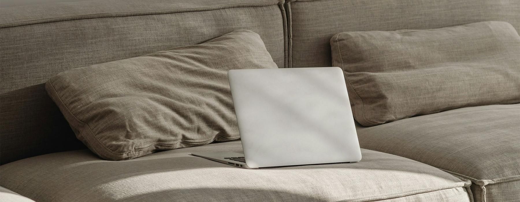 a couch with pillows and a laptop